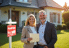 Couple français souriant devant une maison à vendre