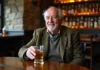 Entre douceur et tradition : les spécificités du whisky irlandais Homme irlandais âgé tenant un verre de whisky dans un pub traditionnel