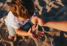 person pouring sand into boys hands