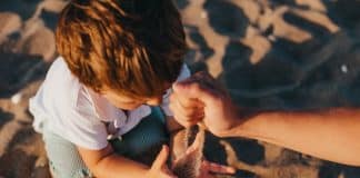 person pouring sand into boys hands