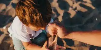 person pouring sand into boys hands